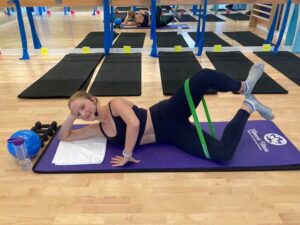 lady laying on the mat with a resistance band on her legs 