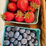 box of strawberries next to a box of blueberries 