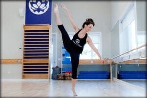 andrea in the dance studio with her leg extended in the air 