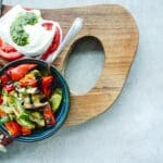 avocados and peppers next to tomatoes and mozzarella on a wooden cutting board